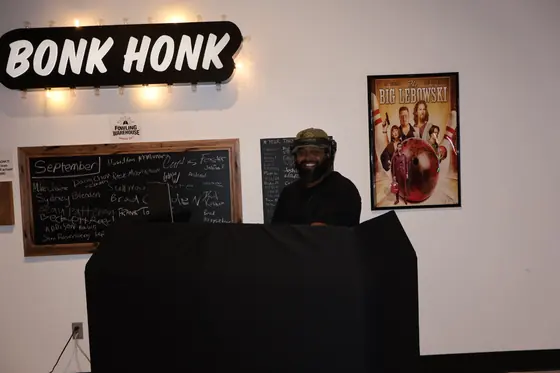 A host at a black podium next to a Bonk Honk sign