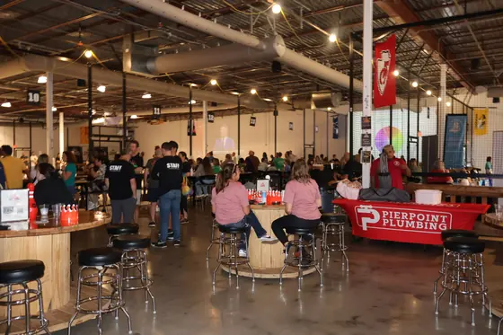 Guests seated at bar tables with the Pierpoint Plumbing table in the background