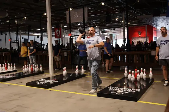 A player mid throw beside a lane of pins
