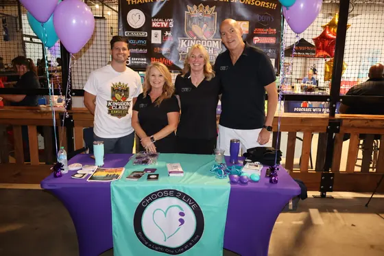 Four volunteers behind a teal and purple nonprofit table
