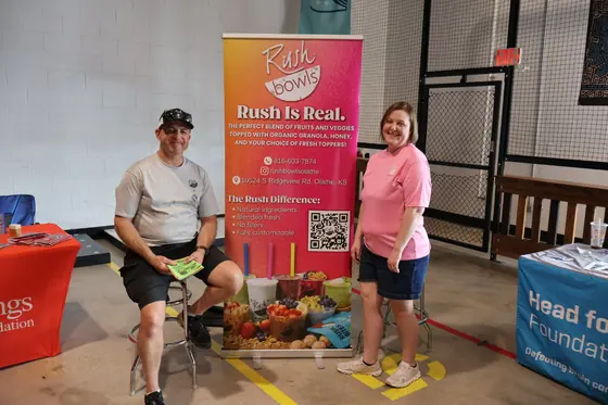 A man and woman at the Rush Bowls banner