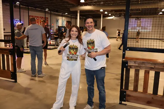 Two emcees holding microphones on the floor beside the lanes