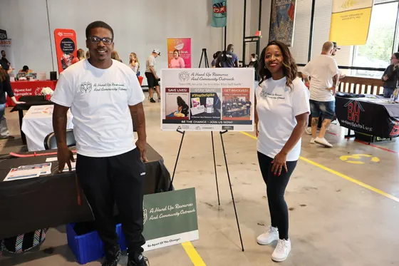 Two volunteers at a table with an easel display