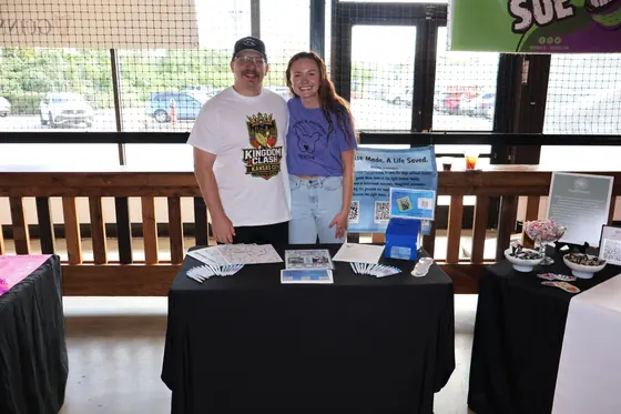 Two volunteers behind a black draped table