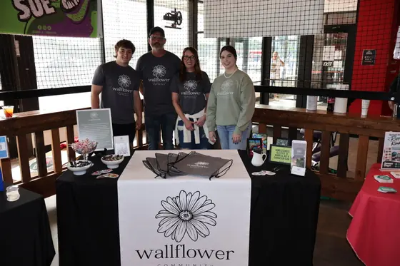 Four volunteers behind the Wallflower Community Outreach table