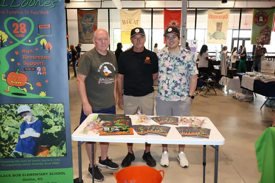 Three volunteers behind a table of fall event brochures