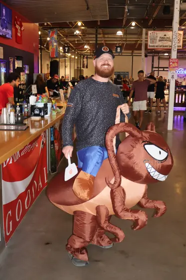 A guest in an inflatable bug costume walking through the bar area